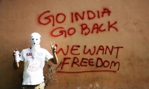 A masked Kashmiri protester shows victory sign after drawing a graffiti on the wall of a building in Srinagar, Indian controlled Kashmir, Tuesday, Sept. 27, 2016. Kashmir is witnessing the largest protests against Indian rule in recent years, sparked by the July 8 killing of a popular rebel commander by Indian soldiers. The protests, and a sweeping security crackdown, have all but paralyzed life in Indian-controlled Kashmir. (AP Photo/Mukhtar Khan)