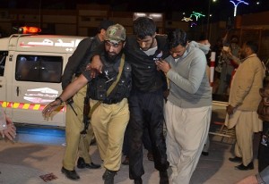A Pakistani volunteer and a police officer rush an injured person to a hospital in Quetta, Pakistan, Monday, Oct. 24, 2016, after two separate attacks in Pakistan.  Gunmen stormed a police training center in the restive southwestern province of Baluchistan Monday, leaving several people wounded, hours after another attack near to Quetta leaving two customs officers dead, authorities said. (AP Photo/Arshad Butt)